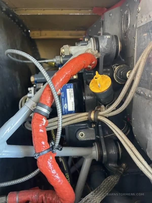 A close-up view of the aircraft's engine compartment, showing various hoses, wires, and mechanical components.