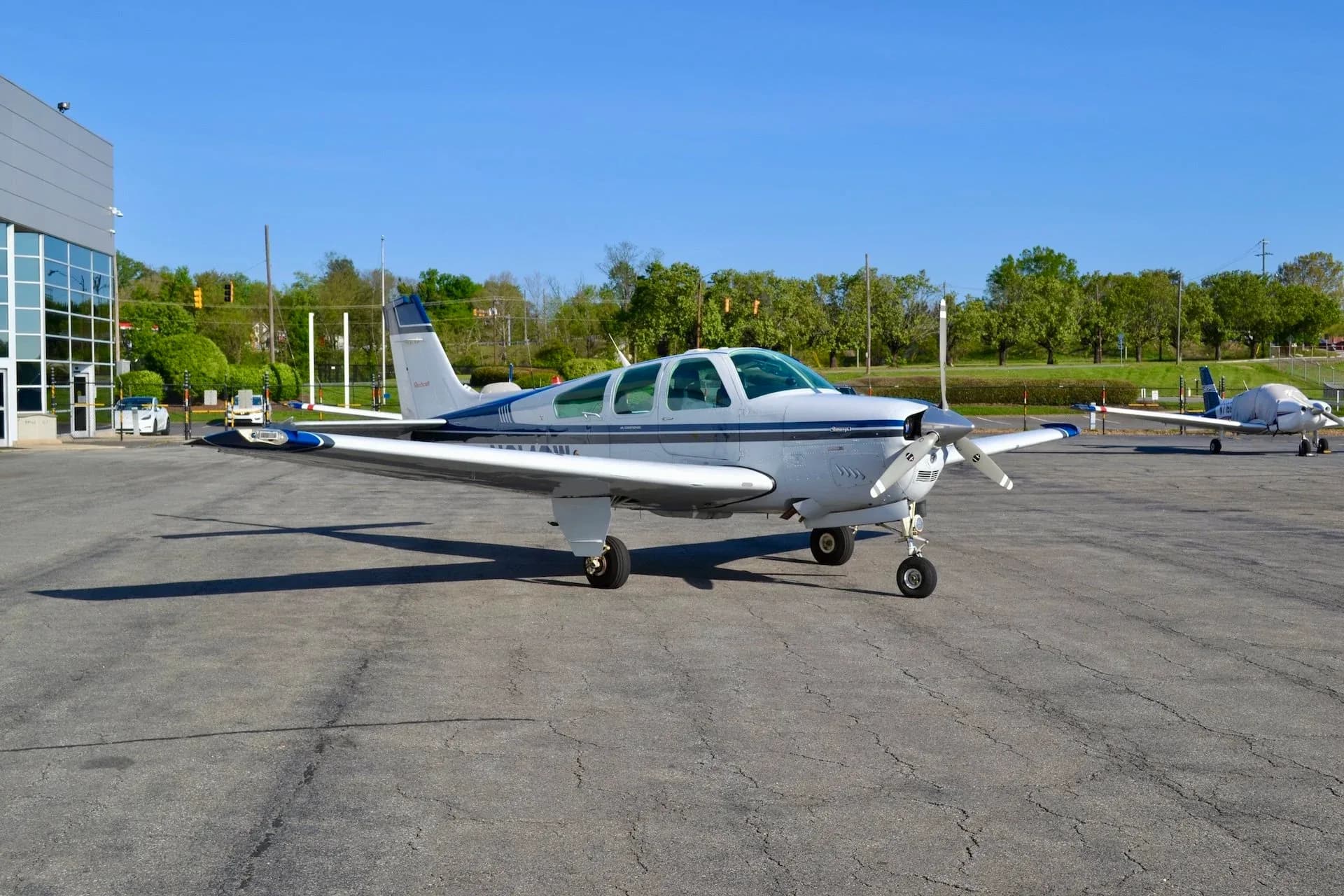 Beechcraft Bonanza N8142W parked on the tarmac in front of a building.