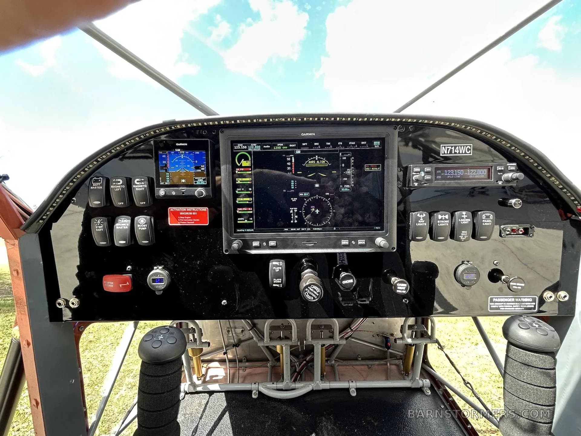 The cockpit of an aircraft, featuring a modern glass panel with multiple Garmin displays and various switches.