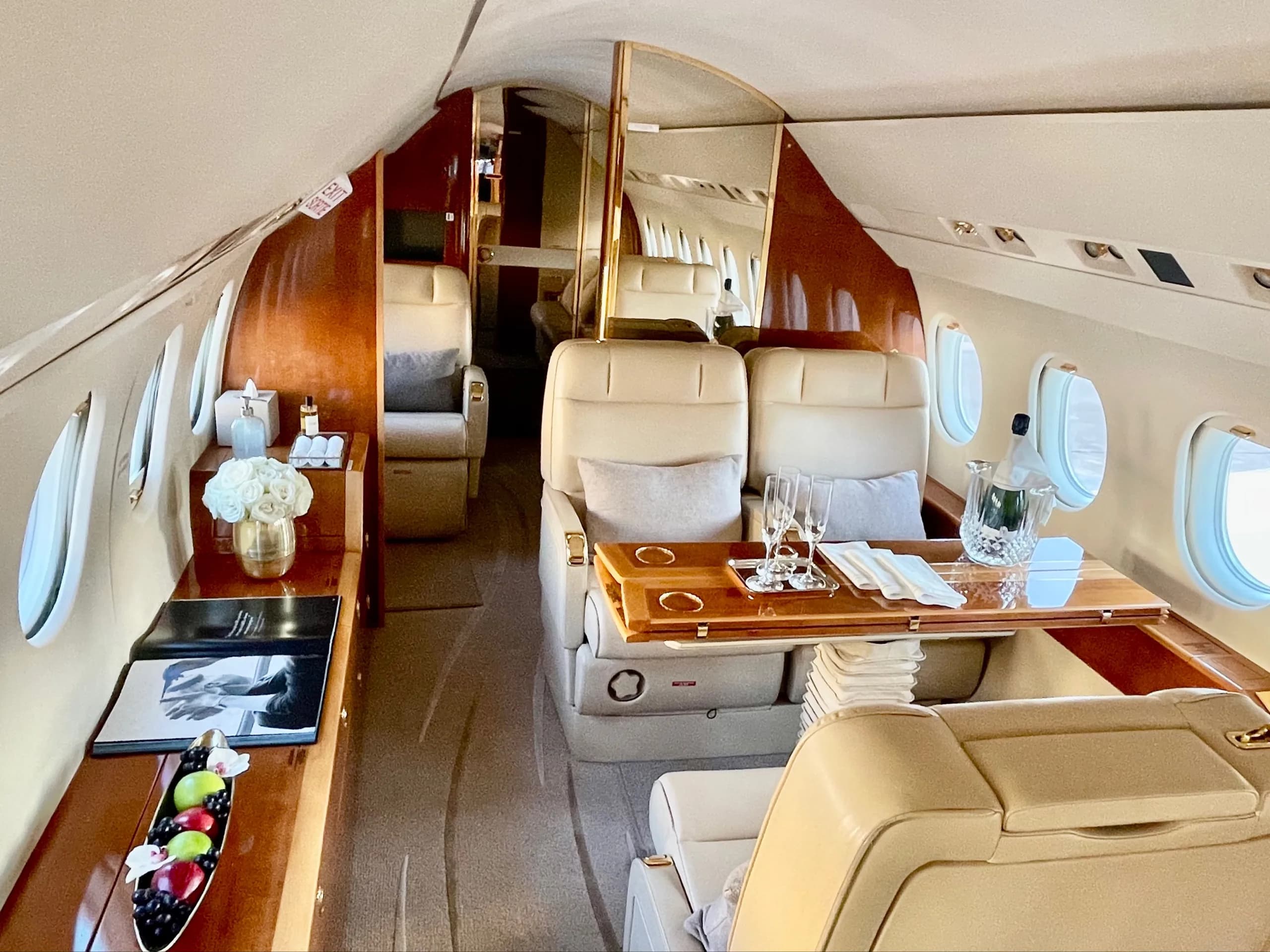 View of the aircraft interior with cream-colored leather seats and wood accents.