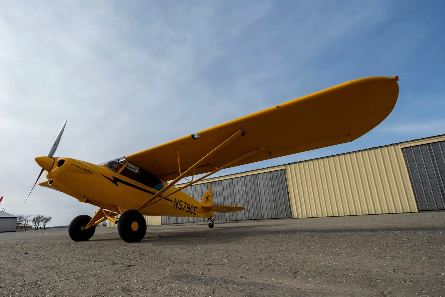 A low-angle view of the yellow CubCrafters Sport Cub S2 aircraft N579CC parked on an airfield.