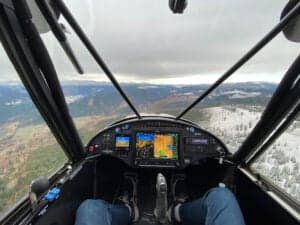 View from the cockpit of an aircraft in flight, showing the instrument panel and the landscape ahead.