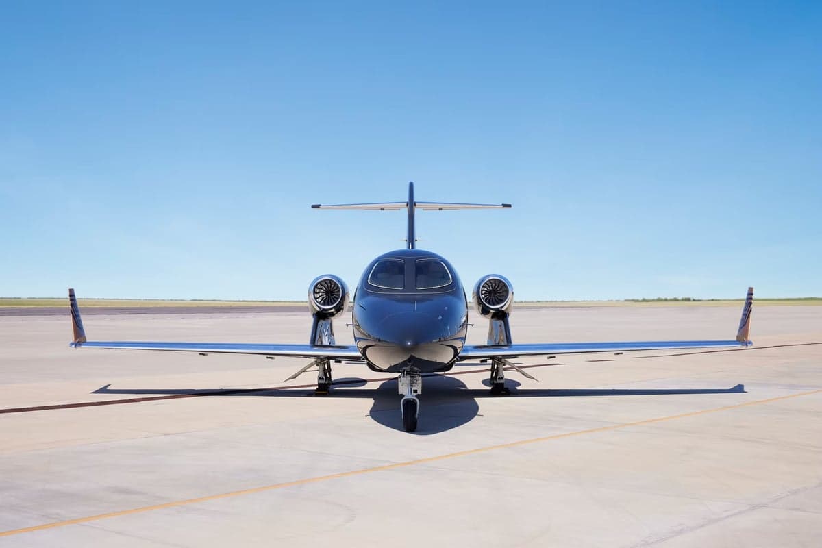 Front view of a dark-colored HondaJet on the tarmac.