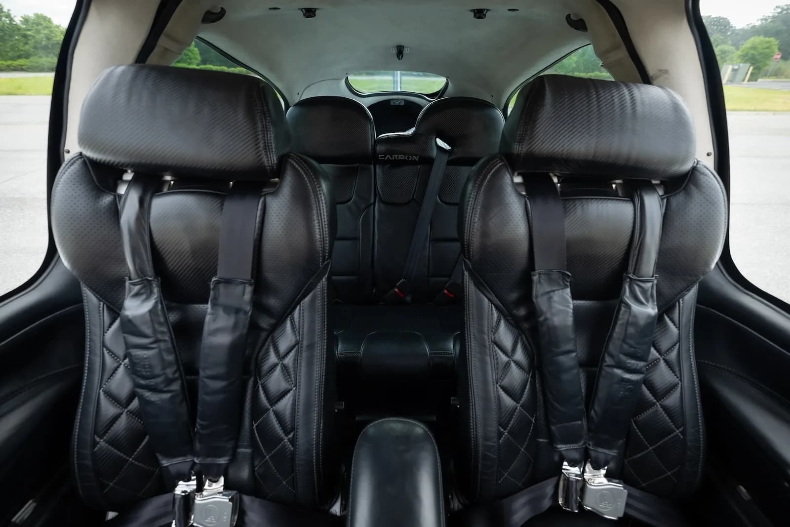 View of the black leather front and rear seats inside the aircraft cabin.