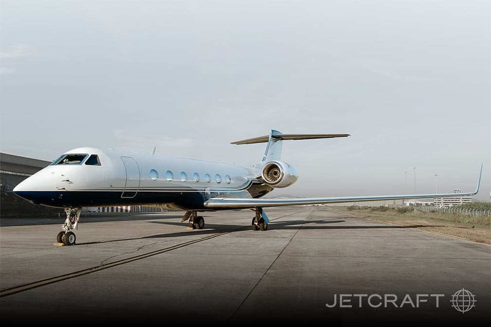 Side view of a silver and blue Gulfstream G650 on the tarmac.