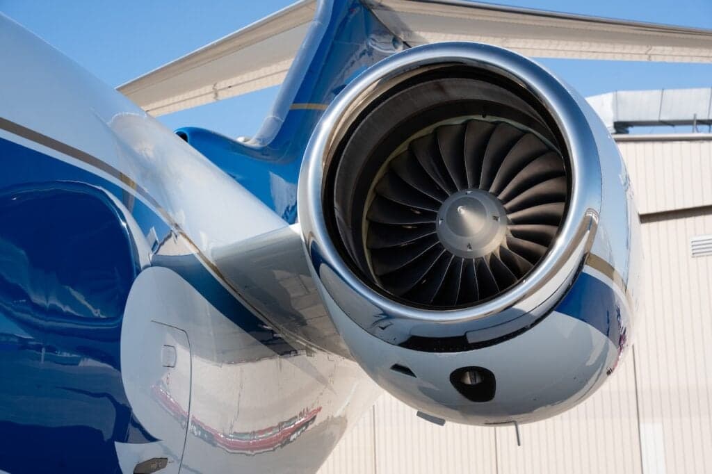 A close-up view of the polished engine intake and blue and white tail section of a business jet.