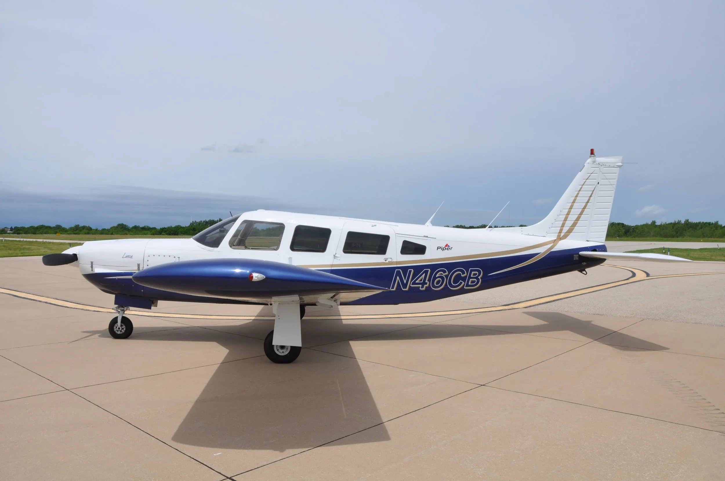 A side view of the white and blue Piper Lance aircraft (N46CB) on the tarmac.