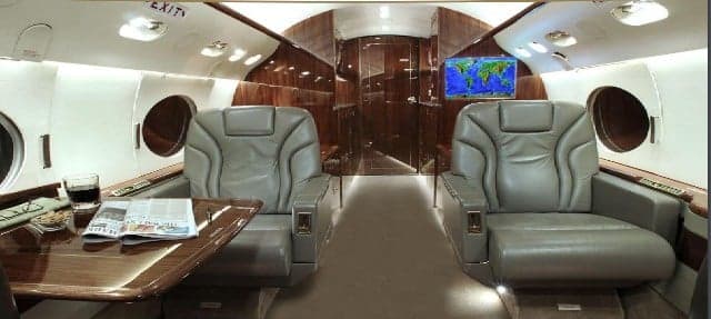 The aircraft's interior features leather seats and wood paneling.