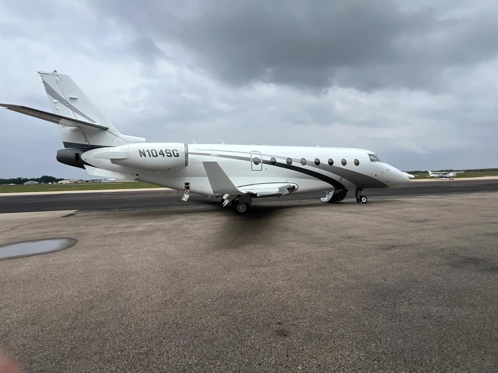 A white and gray jet with tail number N104SG sits on the tarmac.