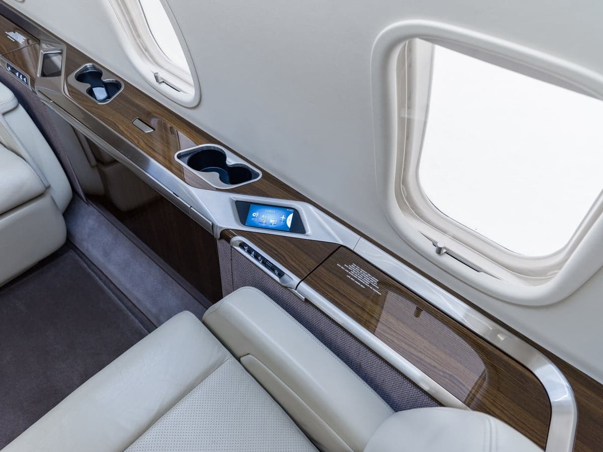 Close-up of a white leather seat and wood trim in the aircraft's interior.