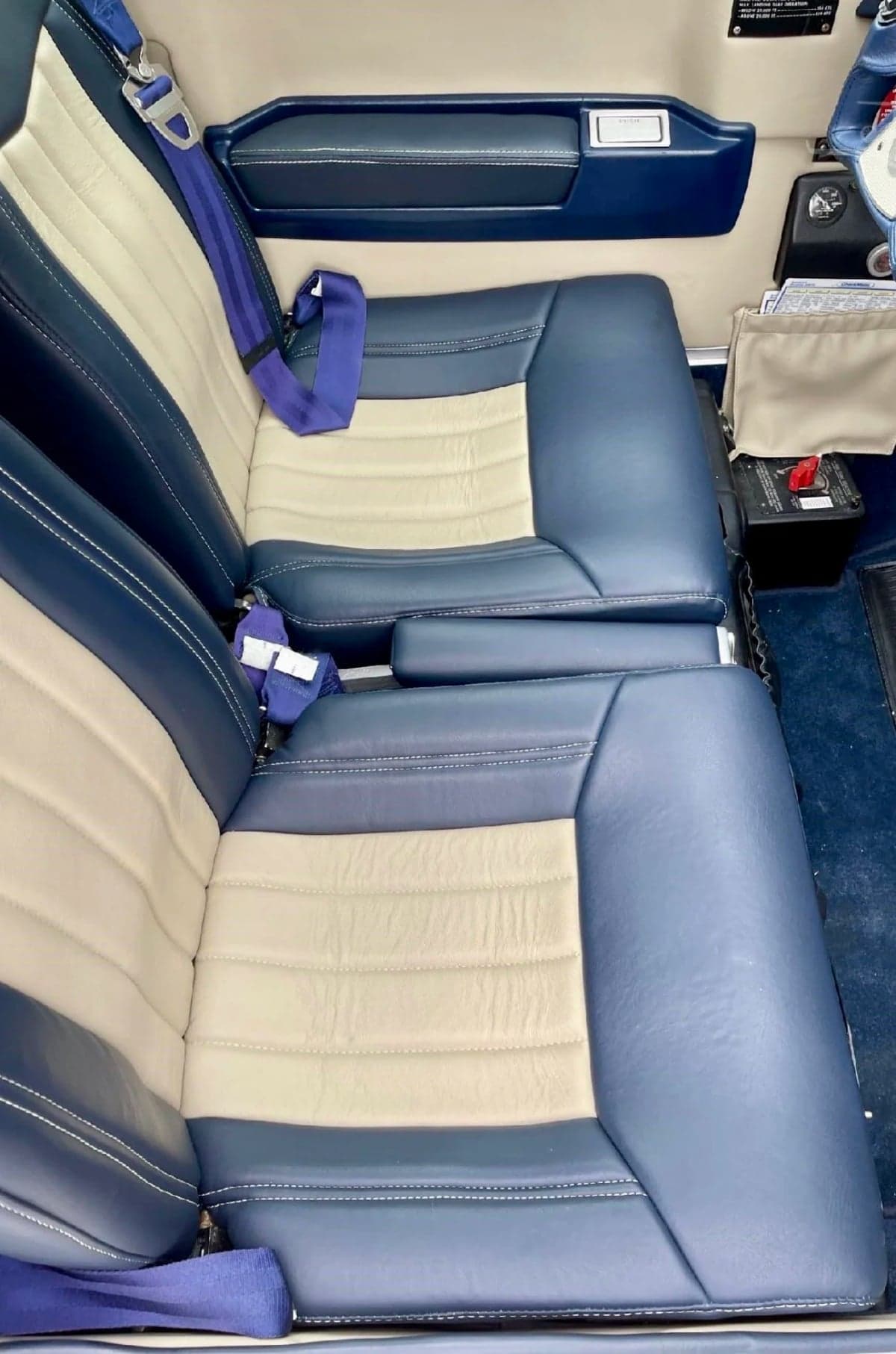 Close-up of the aircraft's blue and beige leather seats with blue seatbelts.