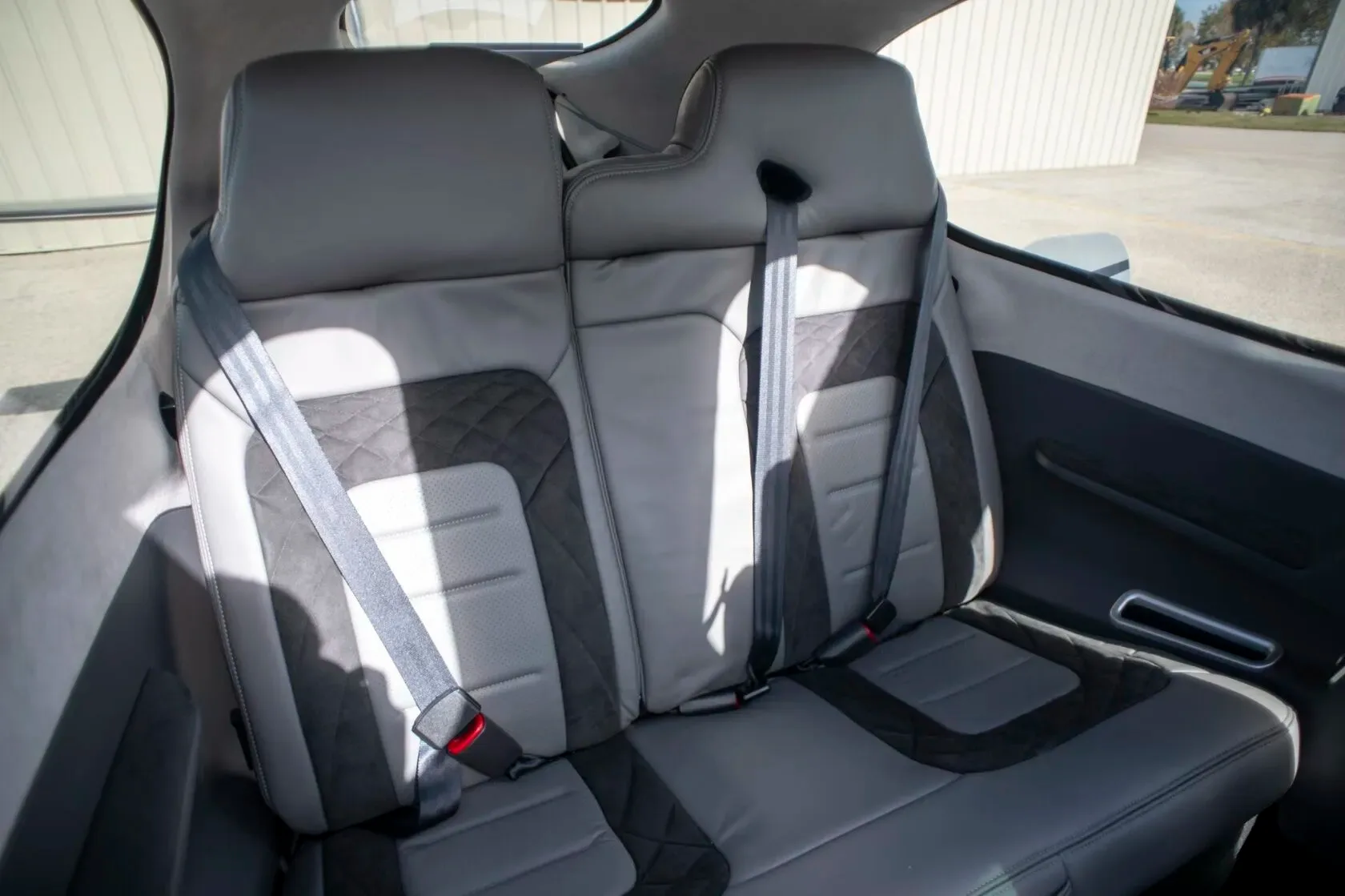 A view of the aircraft's gray and black leather rear seats with seatbelts.