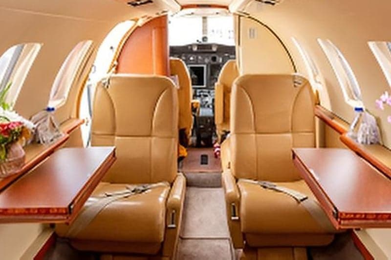 View of the aircraft cabin towards the cockpit with tan leather seats.