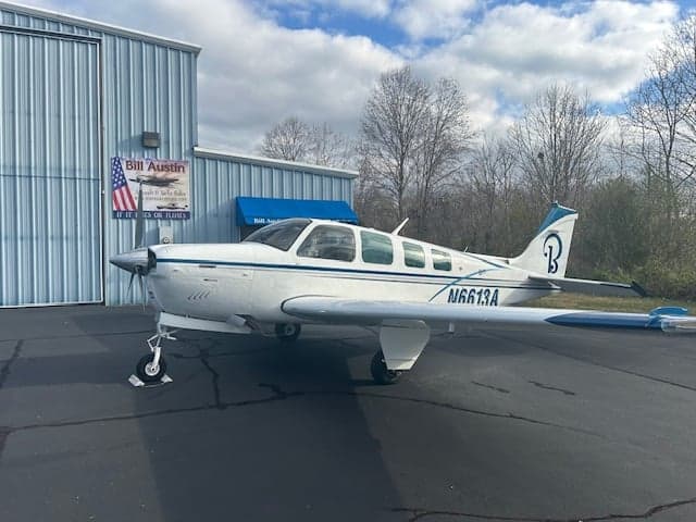 Beechcraft Bonanza N6613A parked on the tarmac in front of a hangar.