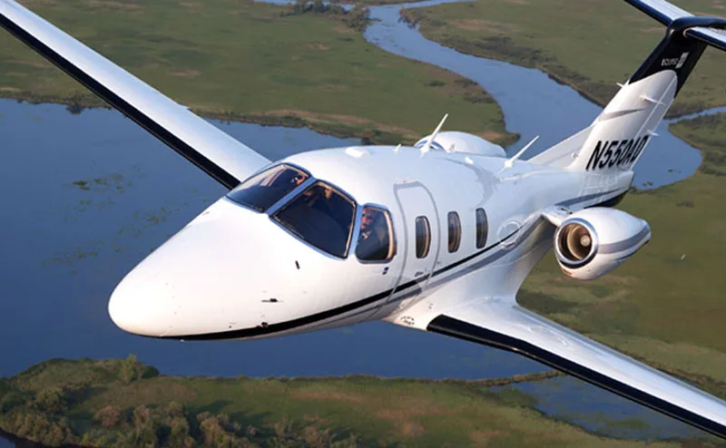 An Eclipse 550 jet in flight over a river.