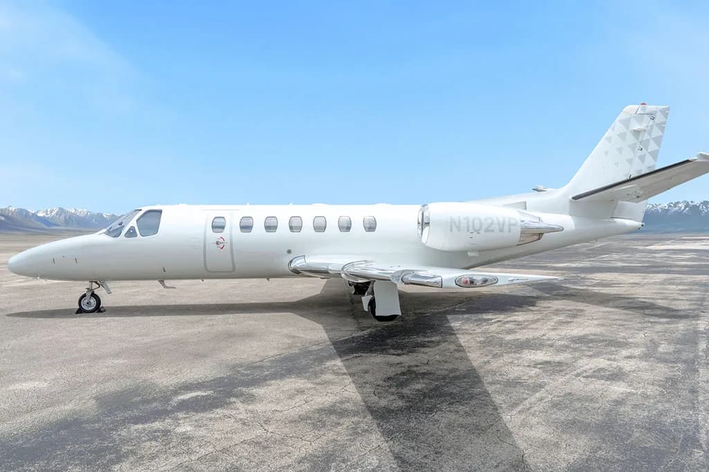 A side view of a white Cessna Citation CJ3 (N102VP) with a geometric pattern on the tail, parked on a tarmac.
