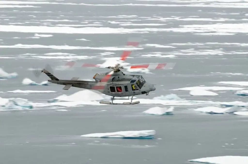 Bell UH-1 Iroquois helicopter flying over icebergs.