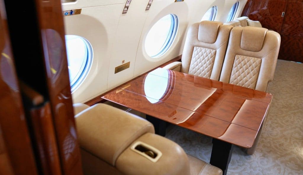 Close up of the front of a white Gulfstream jet with the door open and stairs extended.