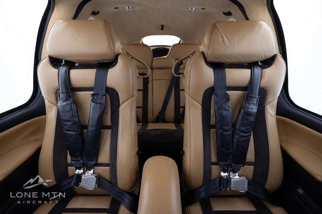 View of the tan and black front cabin seats with seatbelts in a Cirrus SR22 aircraft.