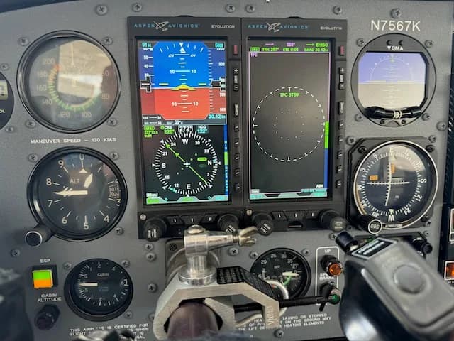 A close-up of the left side of the Cessna 206 cockpit instrument panel, showing digital primary flight displays and analog gauges, with N7567K visible.