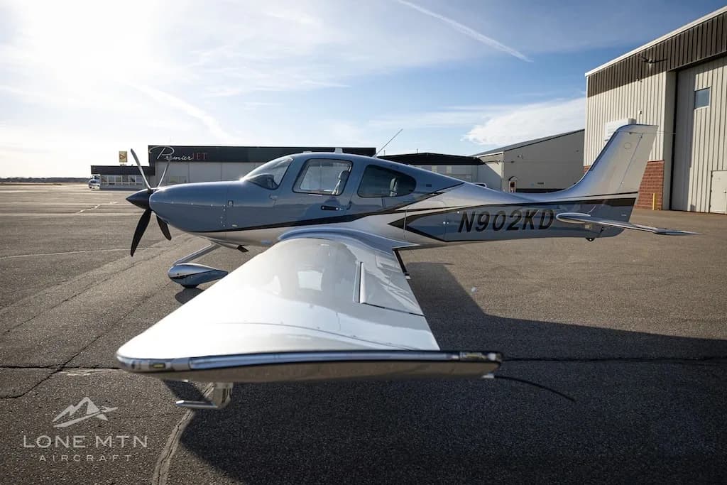 A three-quarter front view of the Cirrus SR22T aircraft, N902KD, in blue and silver, on an airfield.