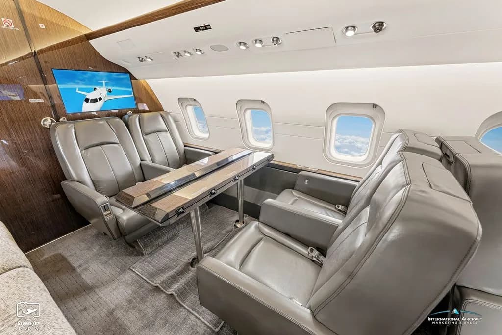 View of the Challenger aircraft cabin with leather seats and wood trim.