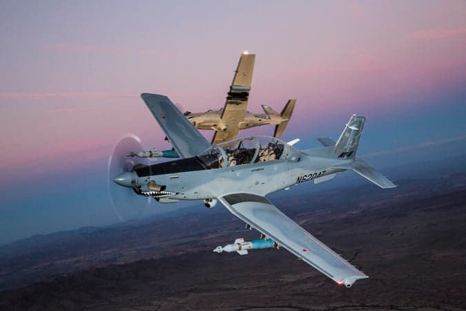 Two AT-6 light attack aircraft in flight with a desert landscape in the background.