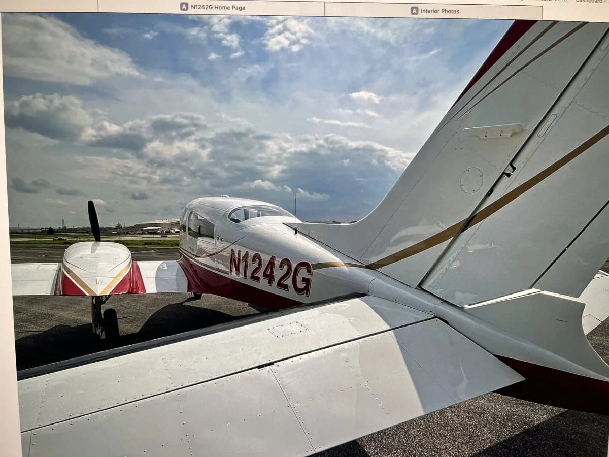 A photo of a screen displaying a rear-quarter view of the N1242G aircraft on an airfield.