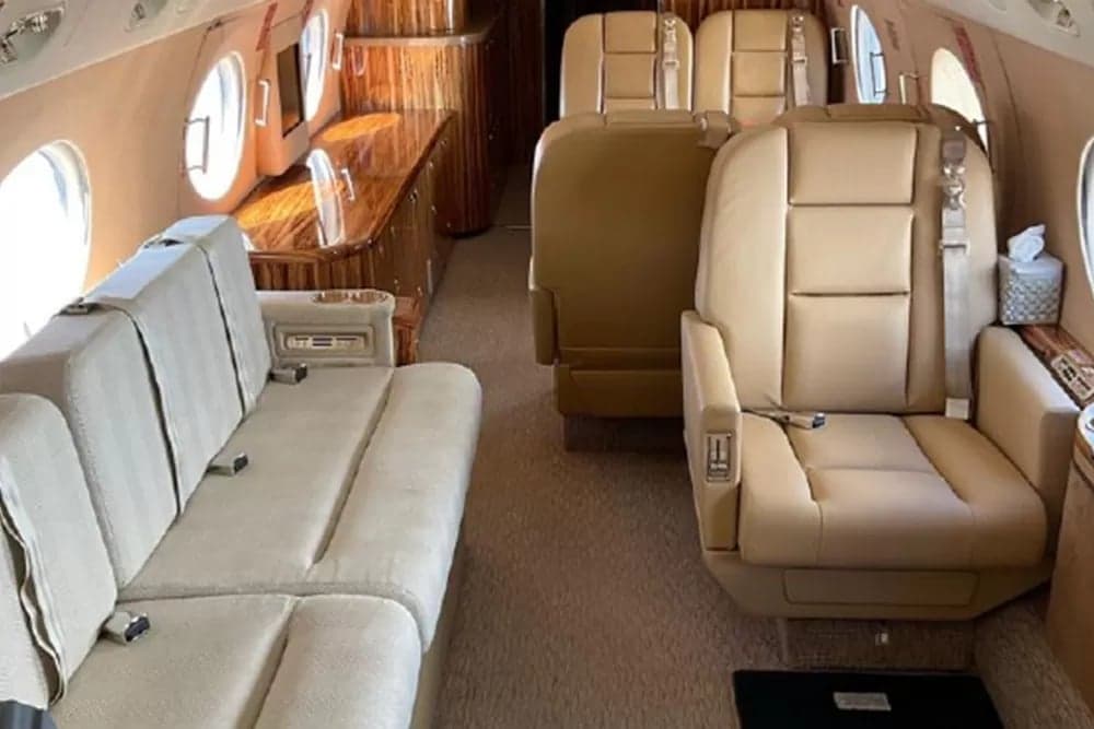 View of the aircraft's cabin with a sofa and tan leather seats.