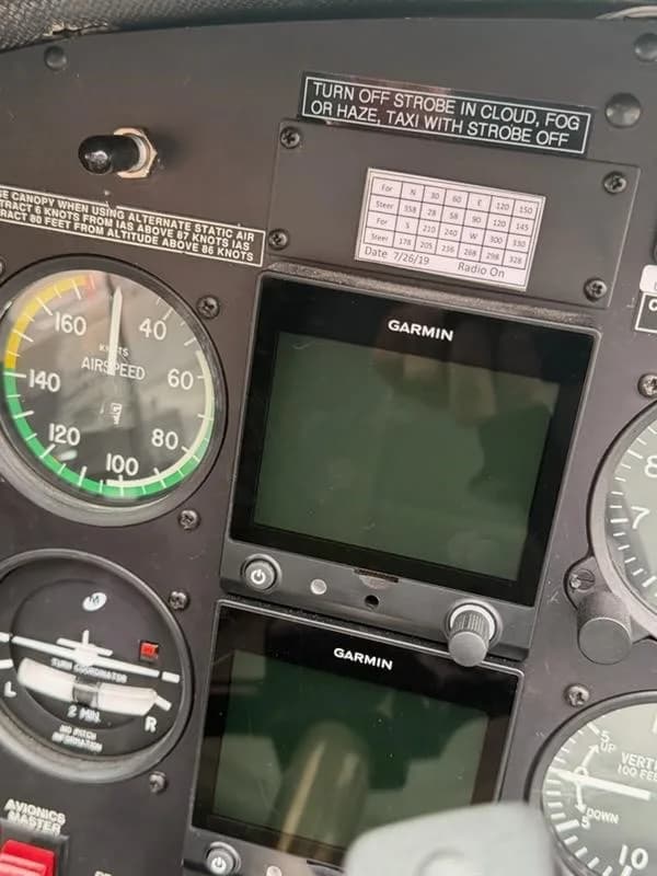 A close-up of the airspeed indicator and two Garmin displays on an aircraft's instrument panel.