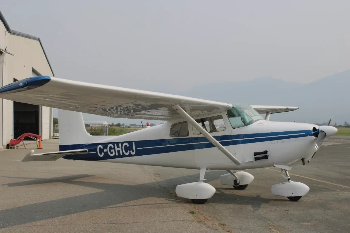 Side view of a Cessna 172 with blue stripe parked on the tarmac.