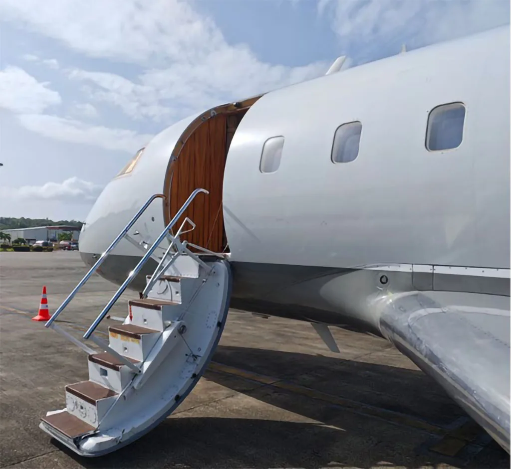 A close-up view of the open main door and extended stairs of the white and grey Bombardier Challenger 604 business jet.