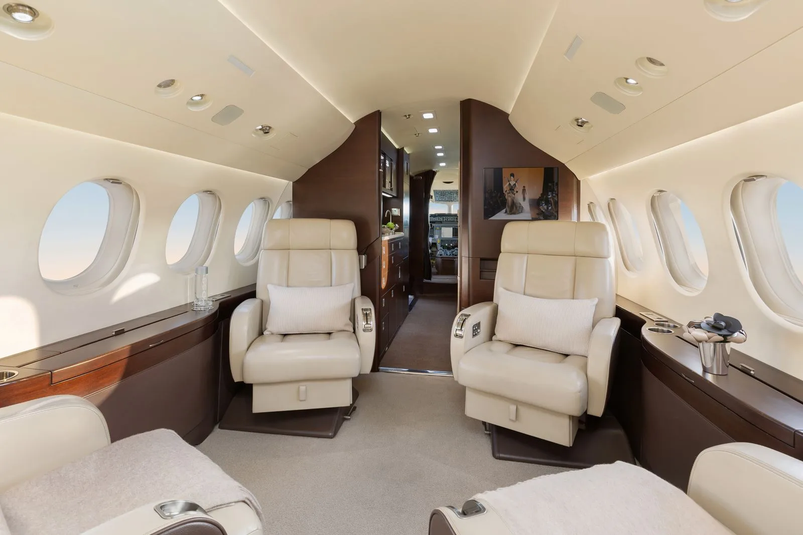 A view of the interior of a Falcon jet with leather seats and a bar.