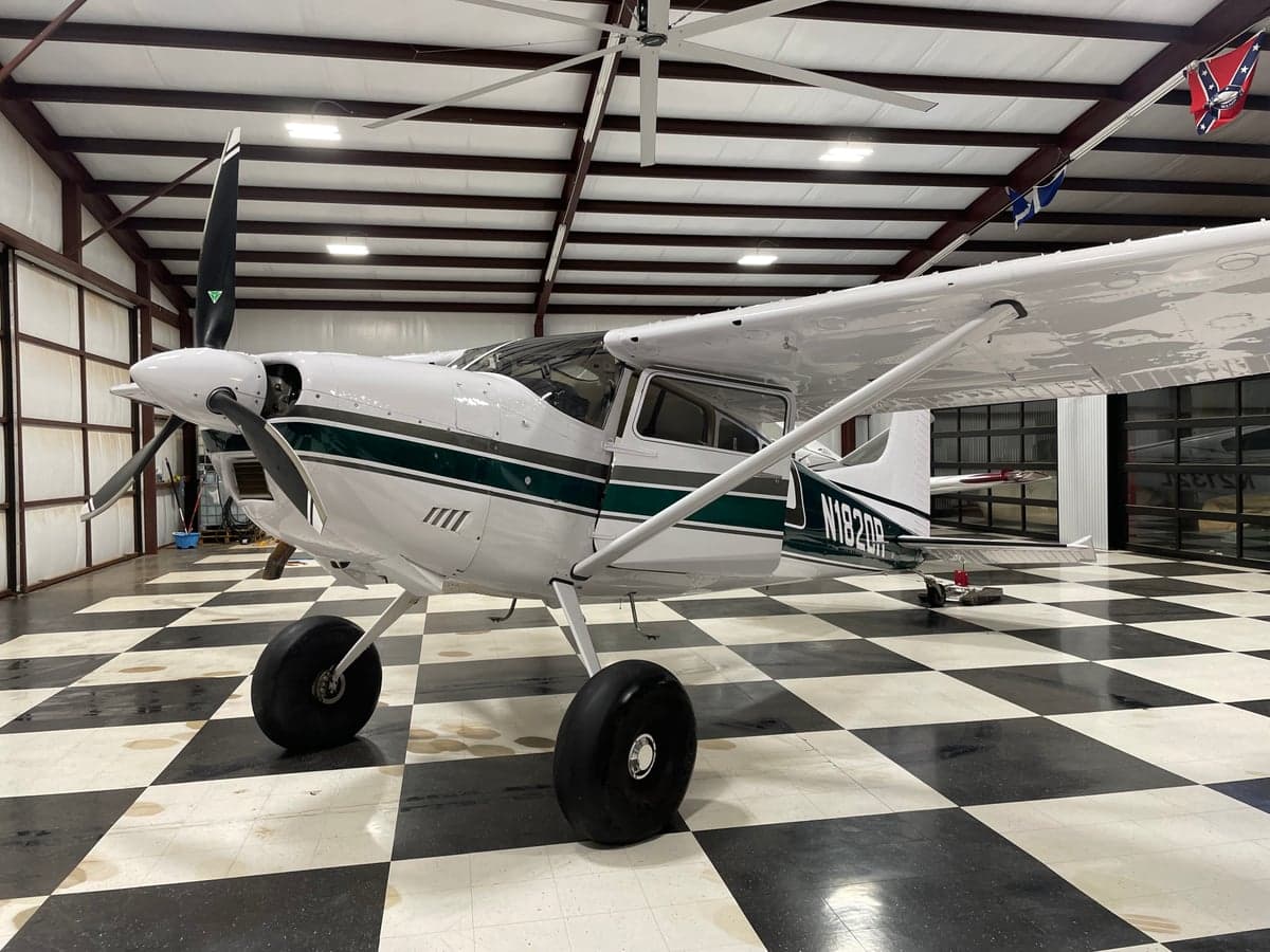 A Cessna 185 Skywagon on the ground in a hangar.