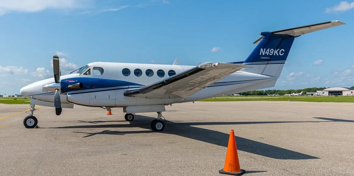 Side view of a white and blue King Air aircraft on the tarmac.