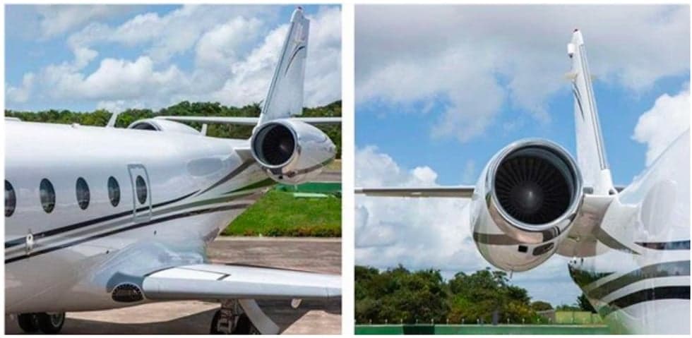 A close-up of the tail and engine of a white jet aircraft with black stripes.