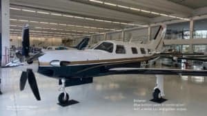Piper PA-46-500TP Meridian aircraft with a blue bottom, white top, and gold stripes parked in a hangar.