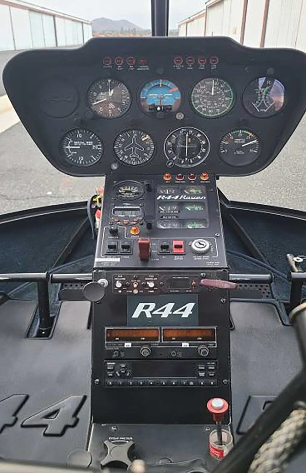 Close-up view of the instrument panel and center console of a Robinson R44 helicopter cockpit.