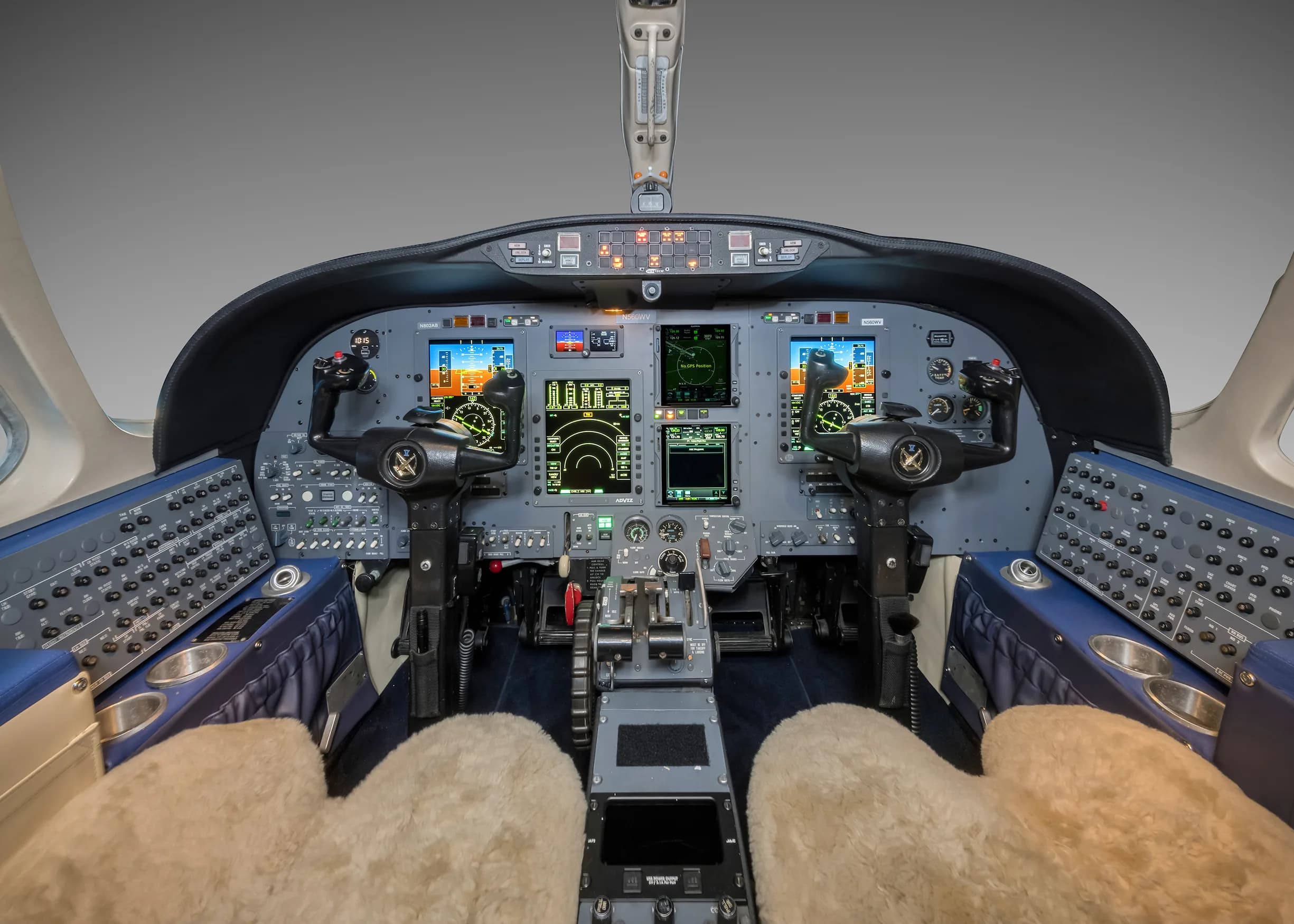 View of the aircraft cockpit with instrument panel and sheepskin seat covers.