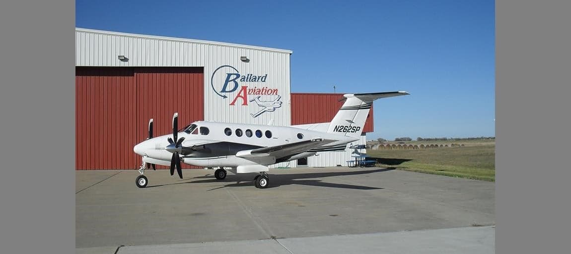 Side view of a King Air aircraft parked in front of a hangar.