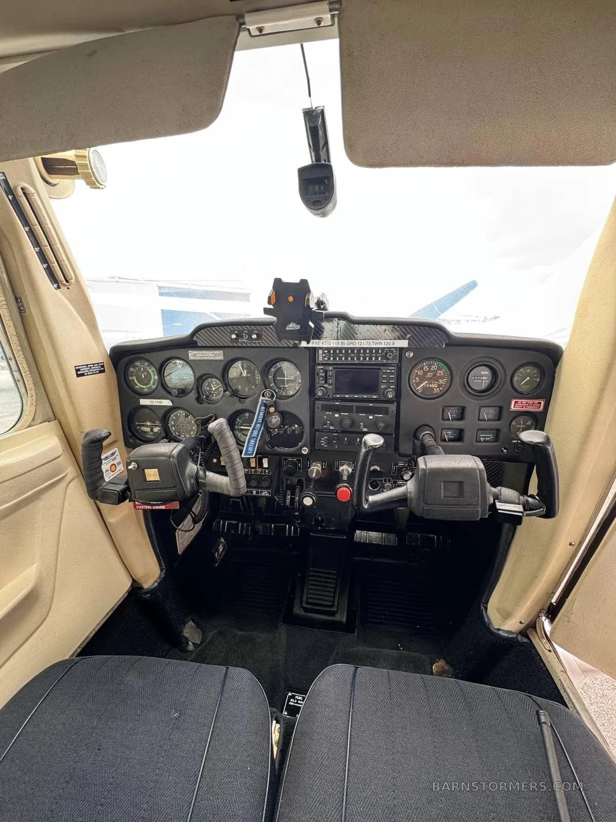 A full view of the cockpit of a small aircraft, showing the instrument panel, yokes, and front seats.