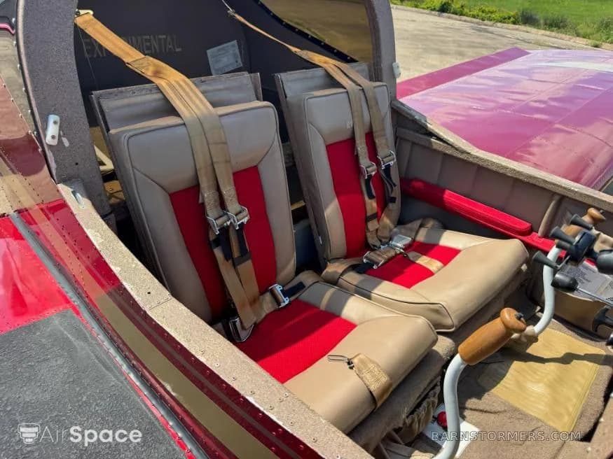 The interior cabin of the Vans RV-6 aircraft, showing two tan and red seats with harnesses.