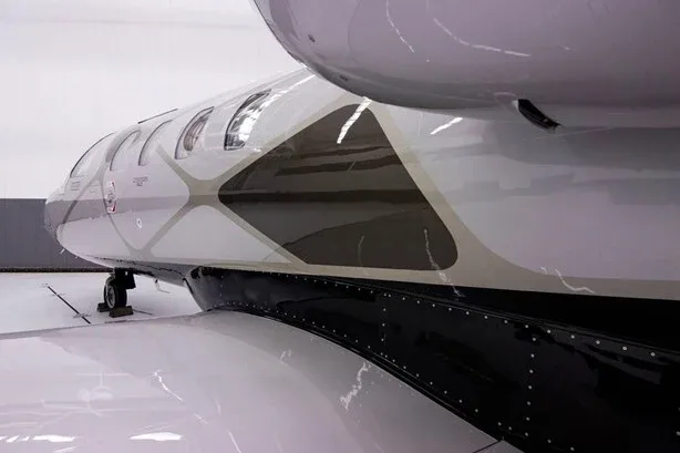 A close-up view of the silver and black paint scheme on the fuselage and wing root of the Cessna Citation M2 jet.