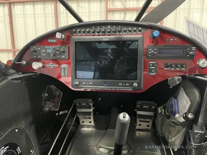 The cockpit of a CubCrafters aircraft, showing the instrument panel with a large Garmin display and controls.