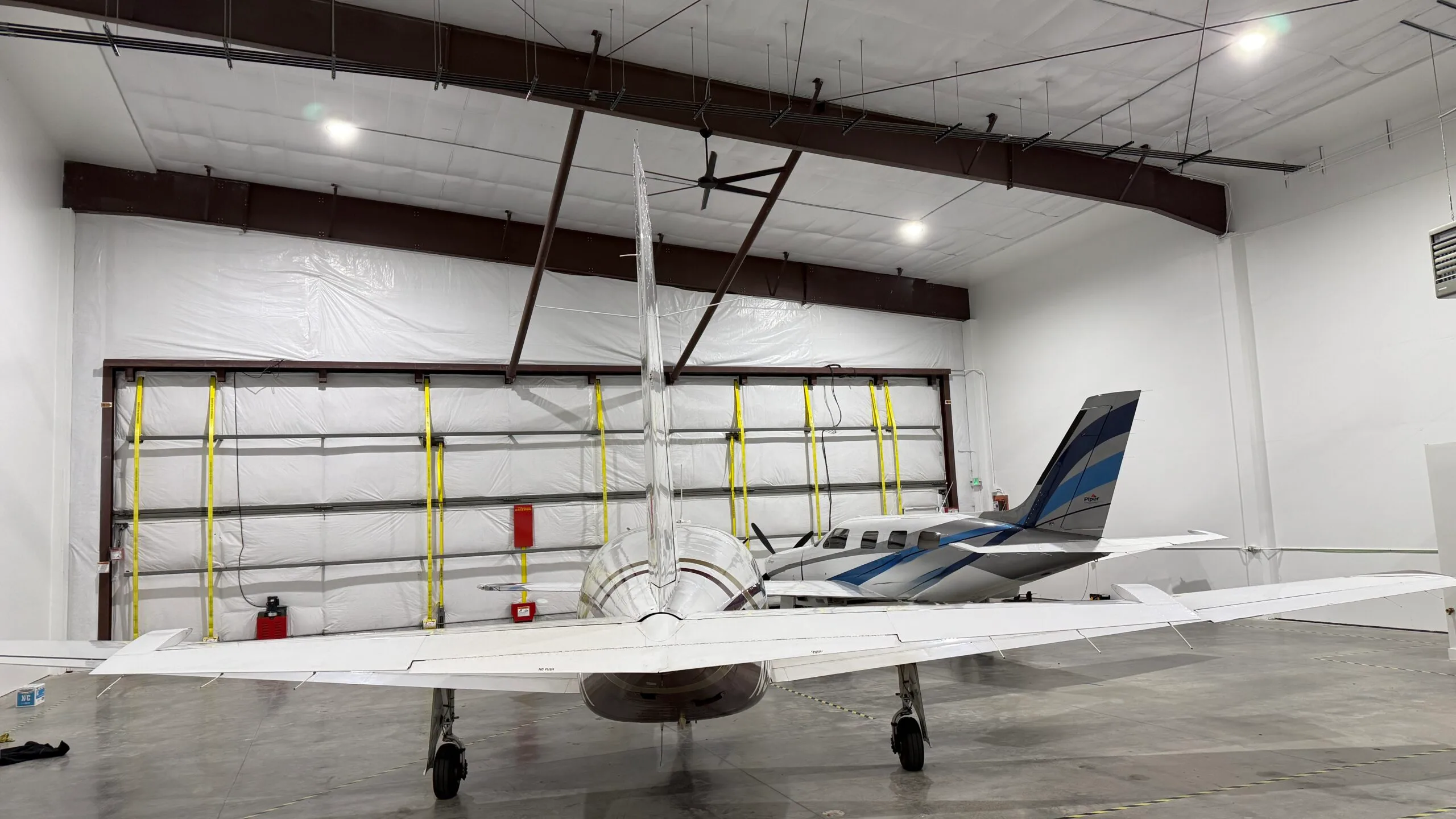 Rear view of an aircraft in a hangar with another aircraft in the background.