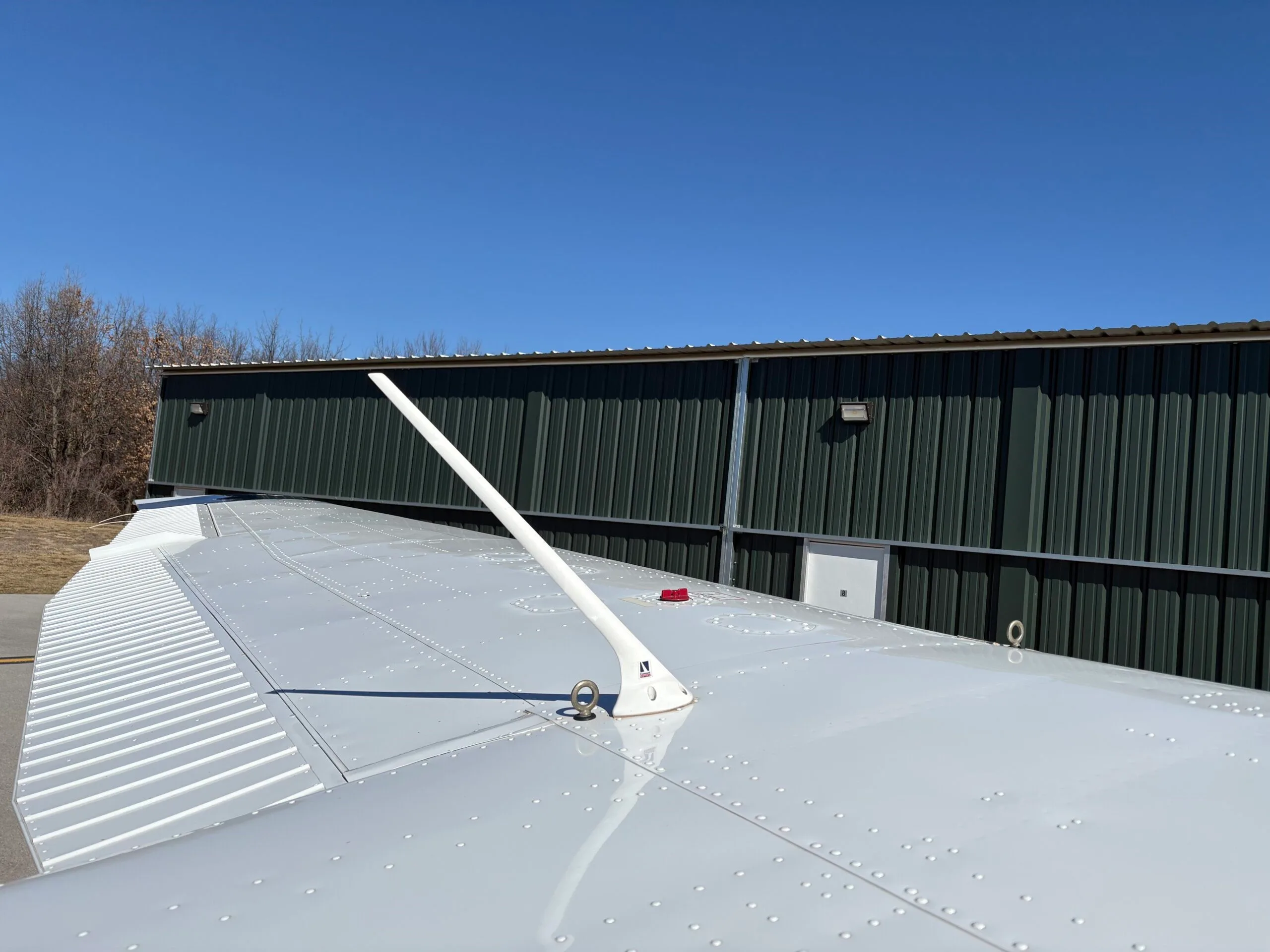 Close-up view of the top of the wing of a white aircraft, showing an antenna.