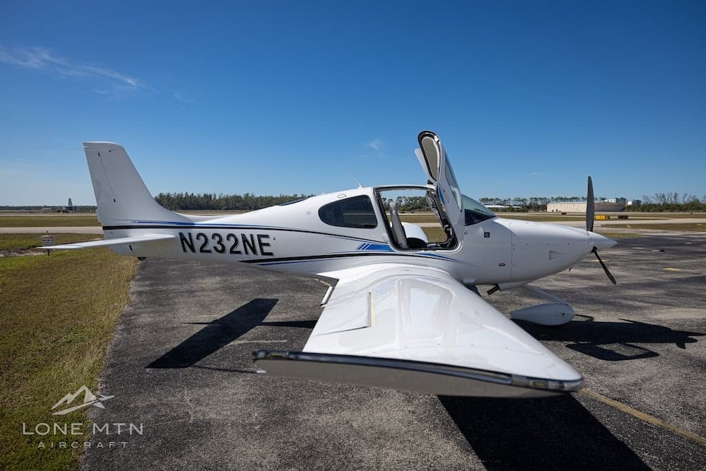 Cirrus SR22T aircraft N232NE parked on the tarmac with open doors.