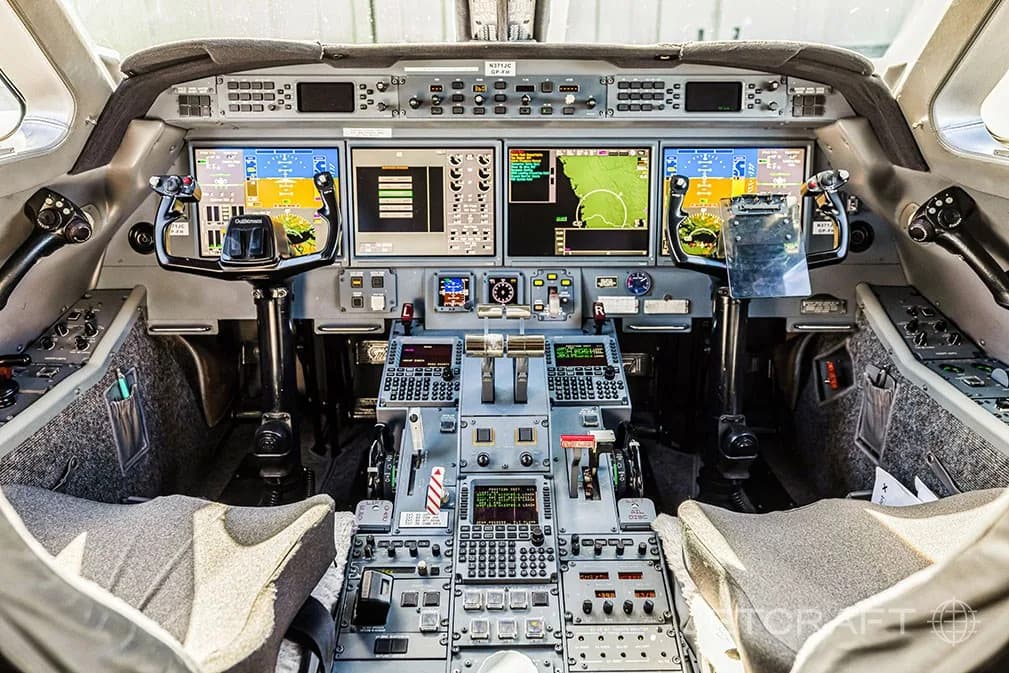 A detailed view of a modern aircraft cockpit with multiple digital displays and control yokes.