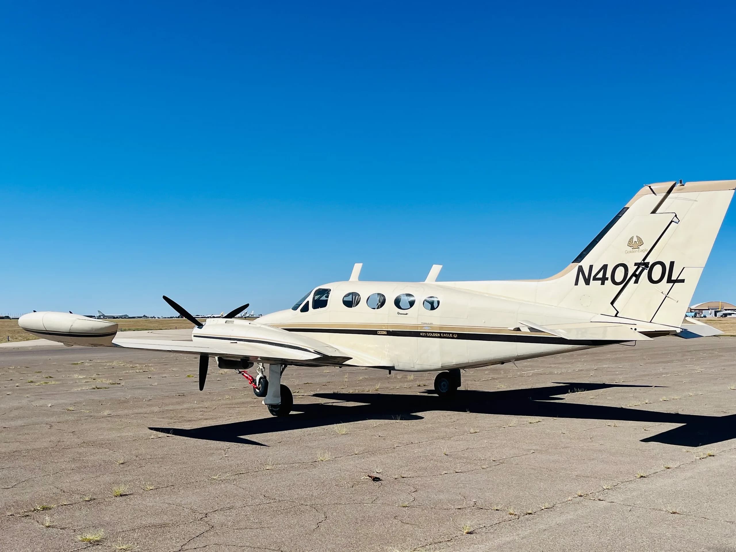 A side view of a white and gold Cessna 421 Golden Eagle (N4070L) parked on an airfield.