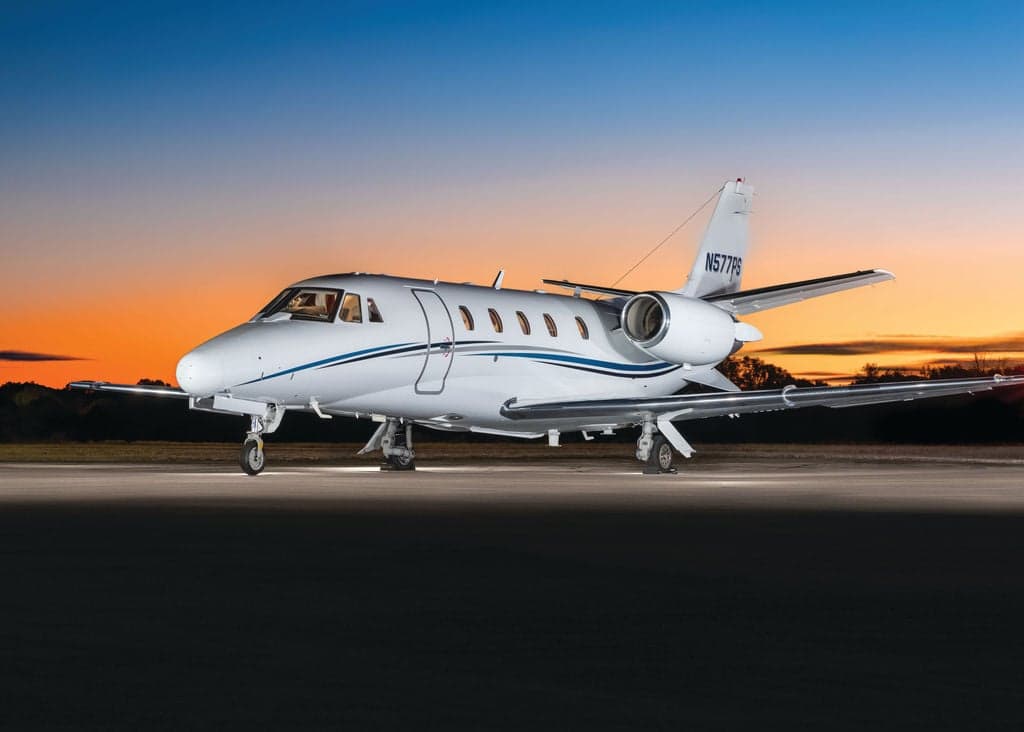 A Cessna Citation CJ3+ aircraft with registration N577PS parked on the tarmac at sunset.